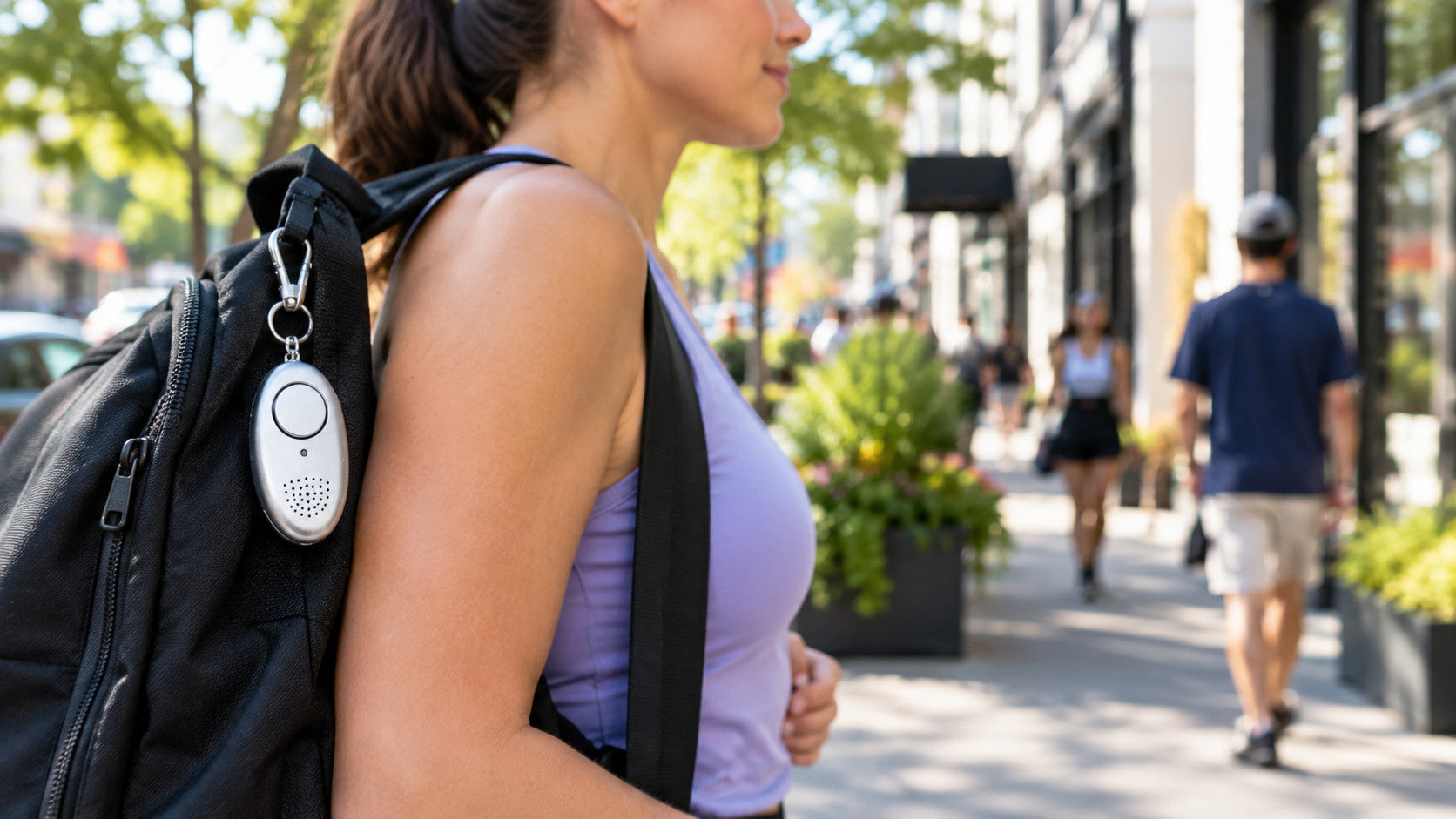 Personal safety alarm clipped to a bag strap while walking outdoors