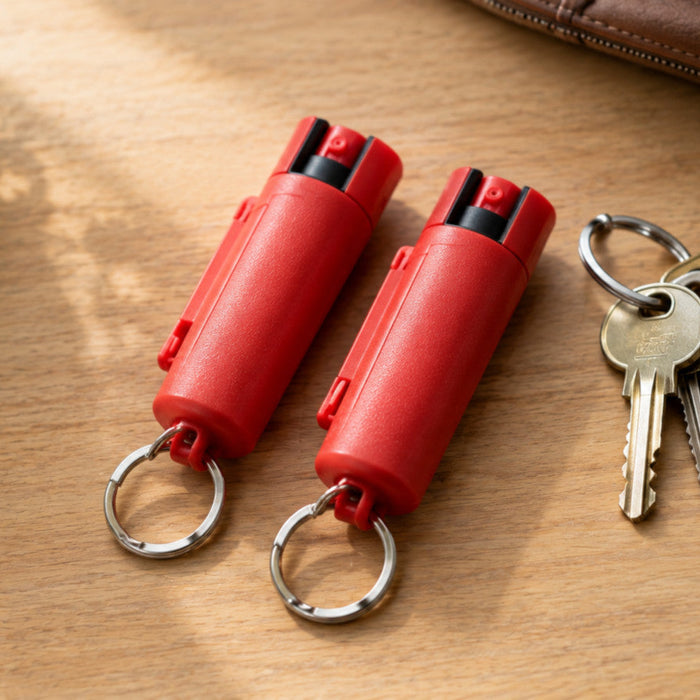 Two identical hard-case keychain pepper sprays side by side next to keys