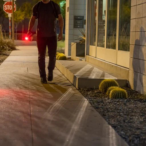 Man using the Red Light of the Strikelight 2 walking on sidewalk at night